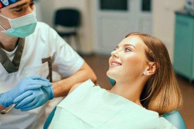 El dentista examina al paciente femenino con los apoyos en la oficina de denal_ _ Foto Premium